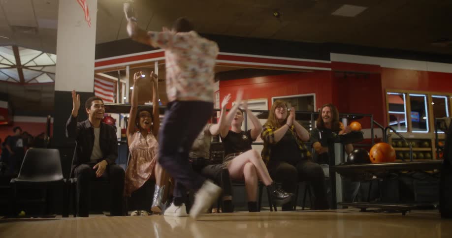 A mans friends cheer for him in the bowling alley