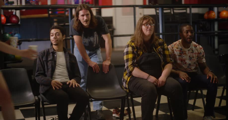 A group of friends celebrates enthusiastically for their friend at a bowling alley