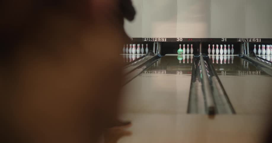 The person throws the bowling ball and gets a sparethe two people watching celebrateby clapping when the person turns a round