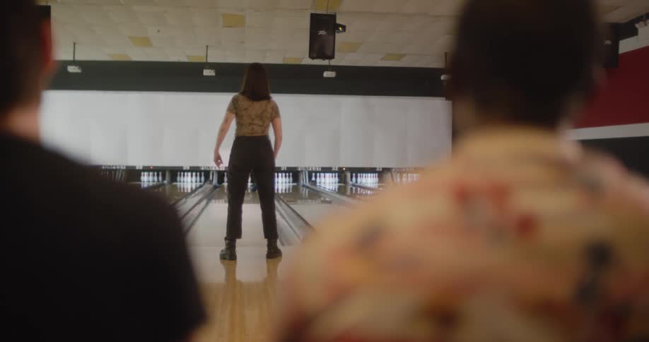 Friends clap after their friend sends bowling ball into the gutter when she bowls