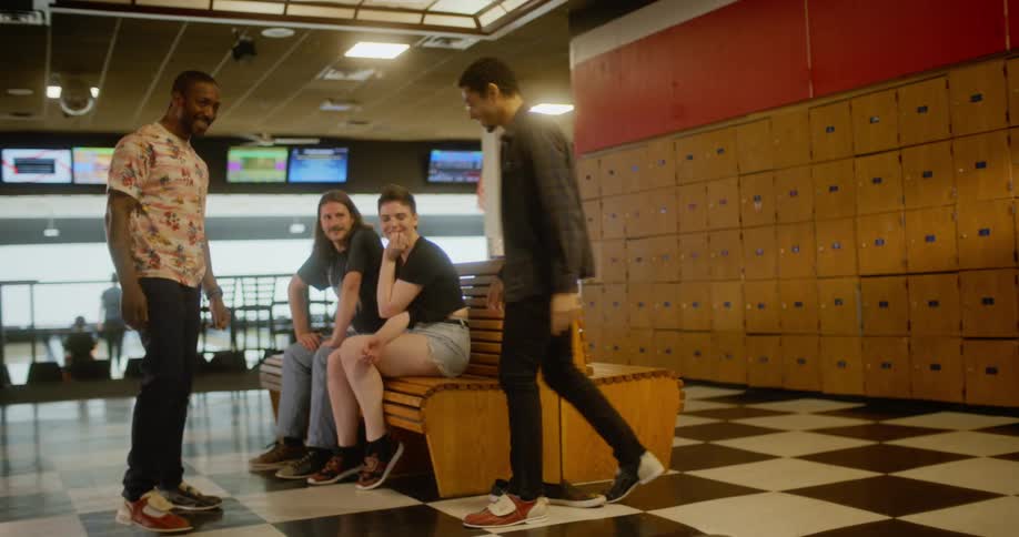 A man doing a moonwalk and some dance steps to two seated women and a man next to him