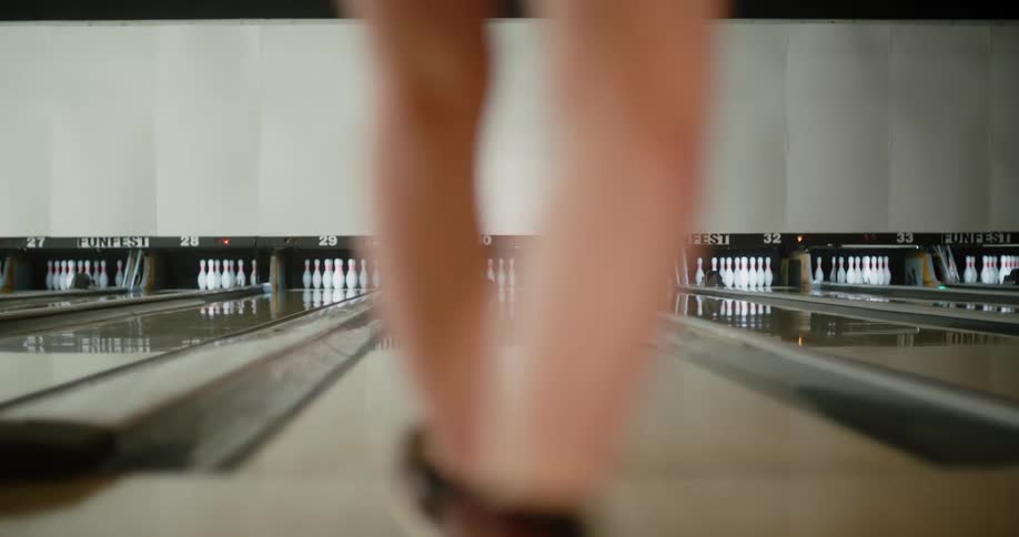A woman throws a bowling ball down a lane knocking down all but three pins