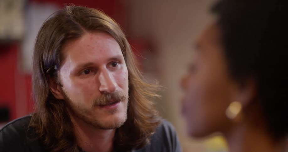 Portrait of a man with a beard sitting talking to a woman