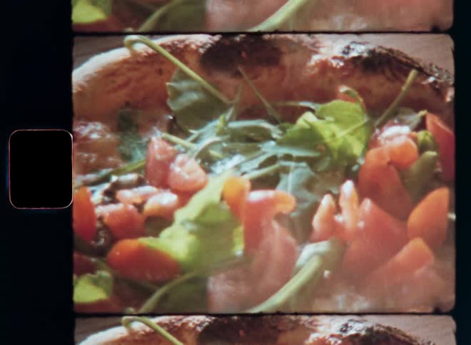 Vegetables being placed on a pizza