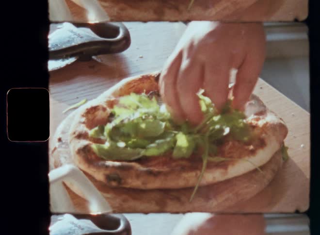 A closeup shot of a hand adding fresh greens to a homemade pizza