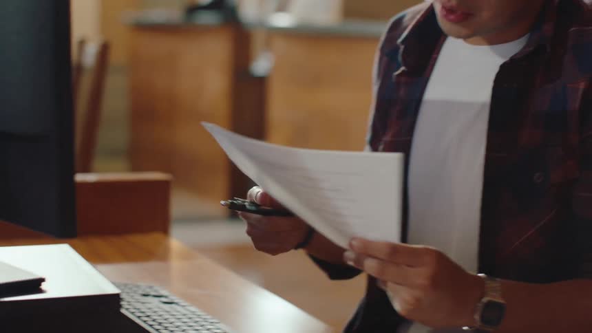 Man sitting at a library computer signing and handing over a document