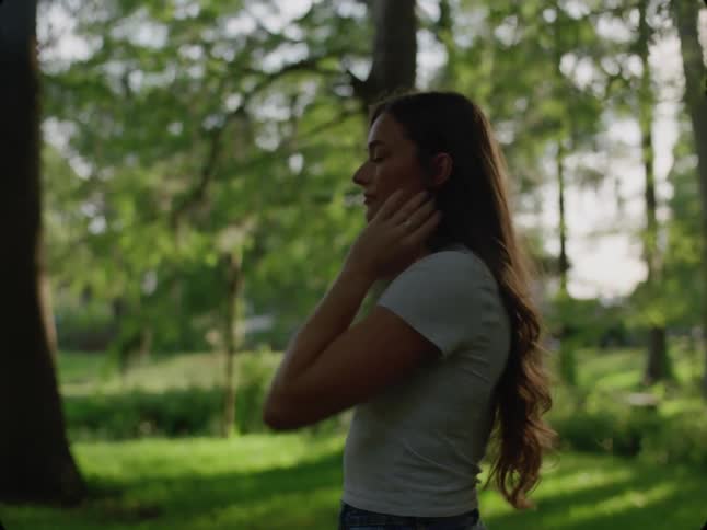 A white teenage girl walks in a suburban park and stops to think