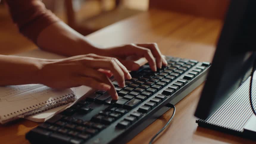 A young woman is using a computer mouse and keyboard in a library