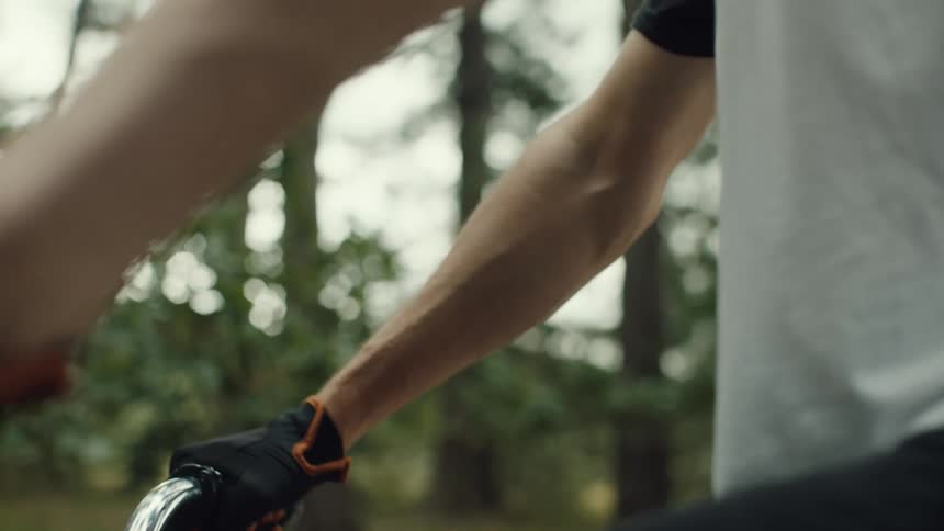 Man riding a bicycle past the woods stops briefly