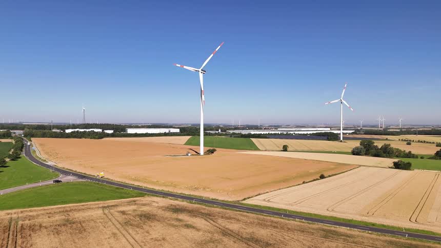A landscape with wind turbines fields and a clear sky