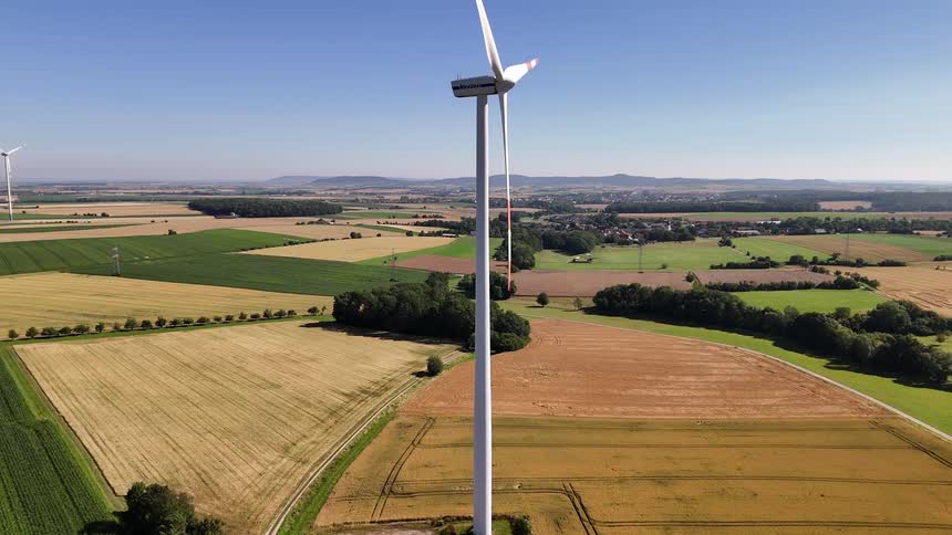 View of a wind turbine in an agricultural field on a cloudless blue sky day