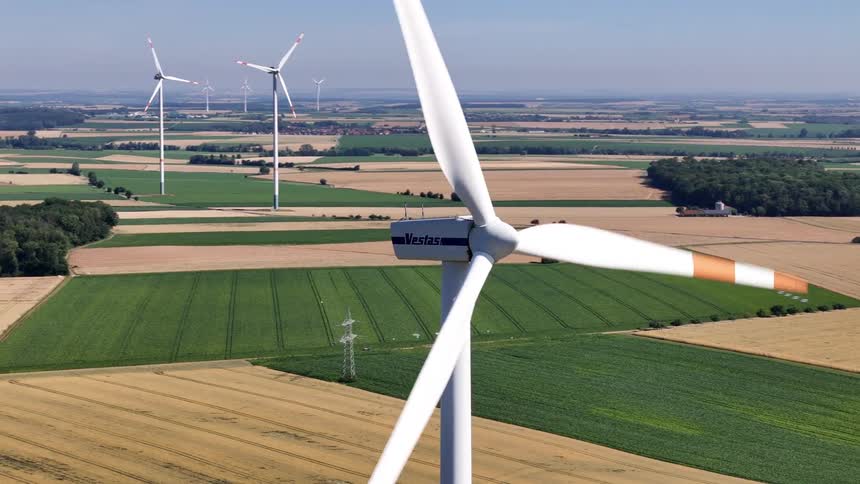 Windmills and solar panels dot an agricultural landscape in a rural area