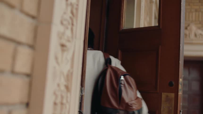 A student with a backpack enters a school in the daytime
