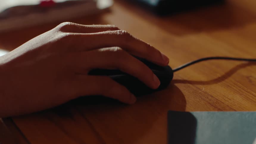 A person types on a computer keyboard and uses a mouse to navigate