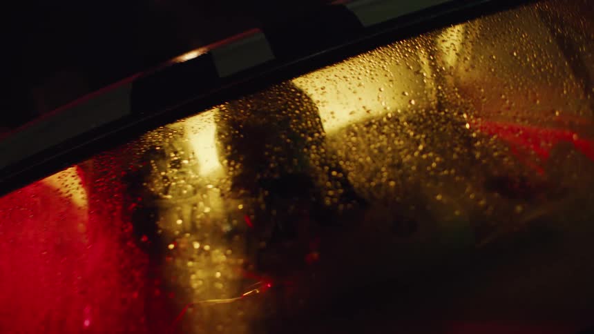 Car with fogged windows parked at night with two people inside kissing warmly