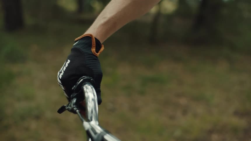 A person wearing black gloves holding a silver bicycle handlebar