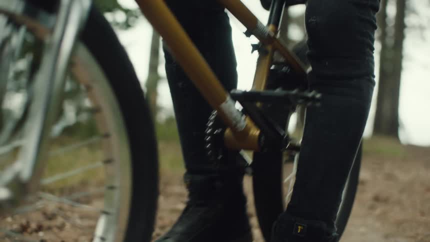 A person gets on their bike in the forest