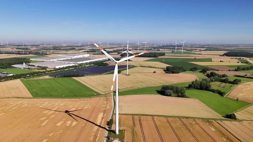 Aerial scenery of agricultural fields with wind energy turbines