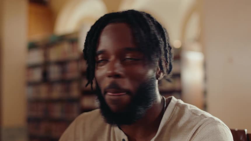 A male student laughs in the library with friends