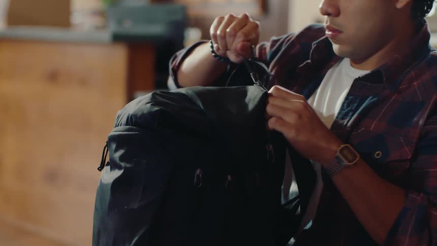 Man sitting in front of the computer taking out his backpack and taking out a book