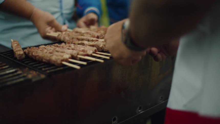 Pair of peoples hands preparing a skewer on the barbecue