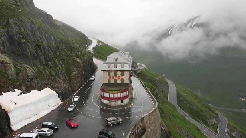 Aerial view of a hotel on the side of a mountain with highways curving around and cars driving by