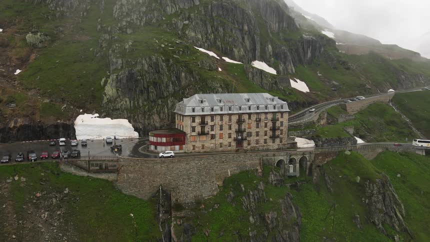 A bus and cars drive past a hotel in a rural area