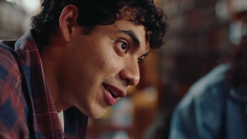 A male student is doing homework while talking to his classmates and laughing