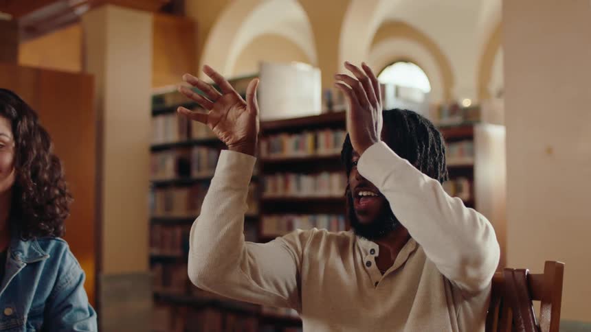 A man tosses a paper ball and cheers in the library