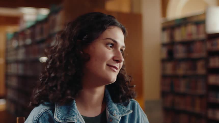 Portrait of a young woman laughing while in a library environment