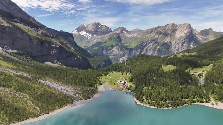 A rural community sits near a lake surrounded by tall mountains