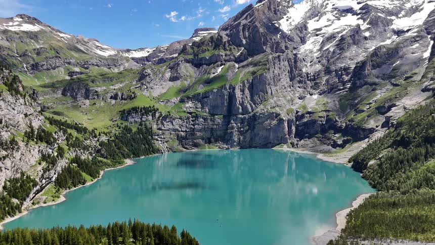 Landscape of a blue lake surrounded by mountains and conifers with snow