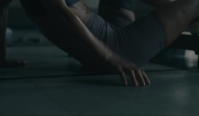 A woman in a gym falls after trying to stretch her leg stepping away from a tire