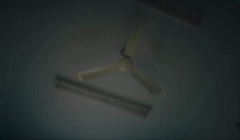 Upward view of a moving ceiling fan and then the lights coming on