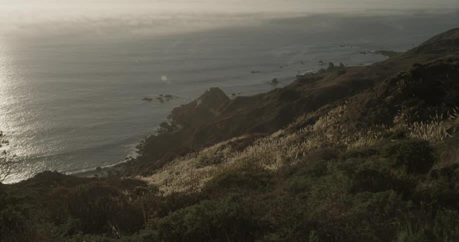 Waves lap the shore at the bottom of a steep hillside