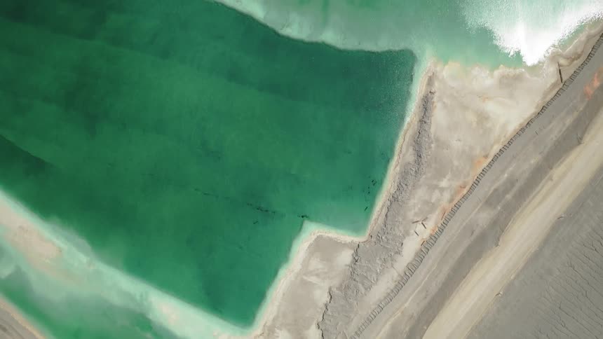 Aerial view of a greenish chemical tailings pile and evaporation pond