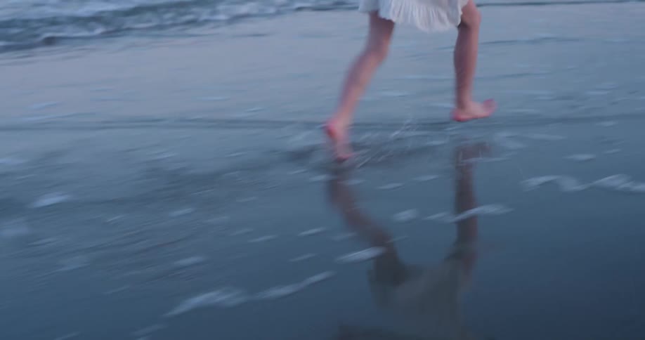 Legs of a child running on the wet sand of the beach