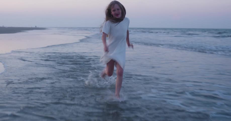 Happy girl runs through the surf on an overcast day