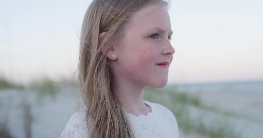 Portrait of a blonde girl with a smile on her face at the beach