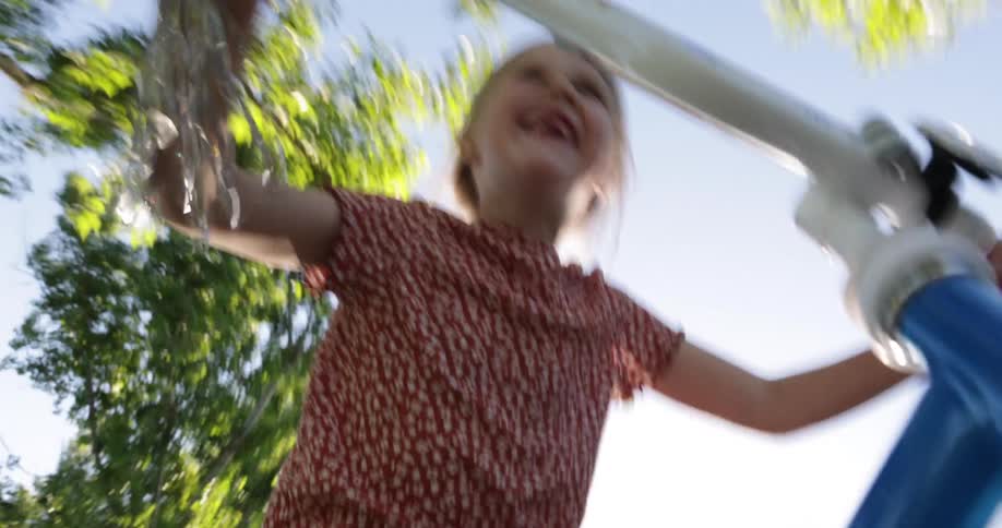 A young girl rides a blue bicycle on a sunny summer day