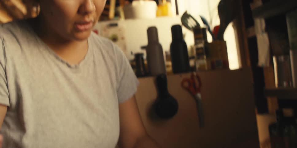 A mother teaches her son how to chop an onion in the kitchen