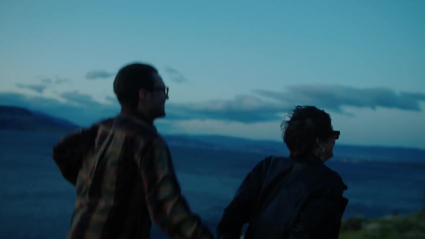 Couple running hand in hand running on a hill by a lake