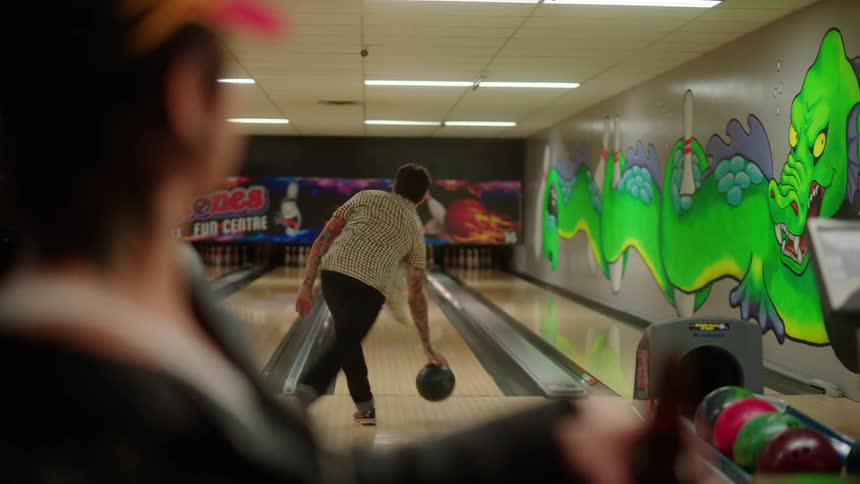 A man throws the bowling ball and smiles