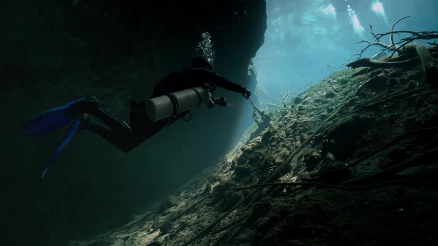 A scuba diver is traveling through the cave
