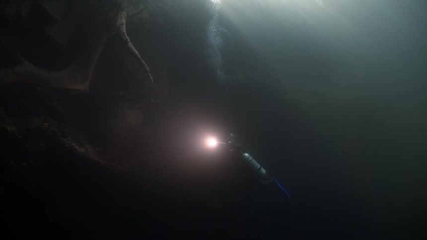 Diver submerged in an aquatic cave with a flashlight