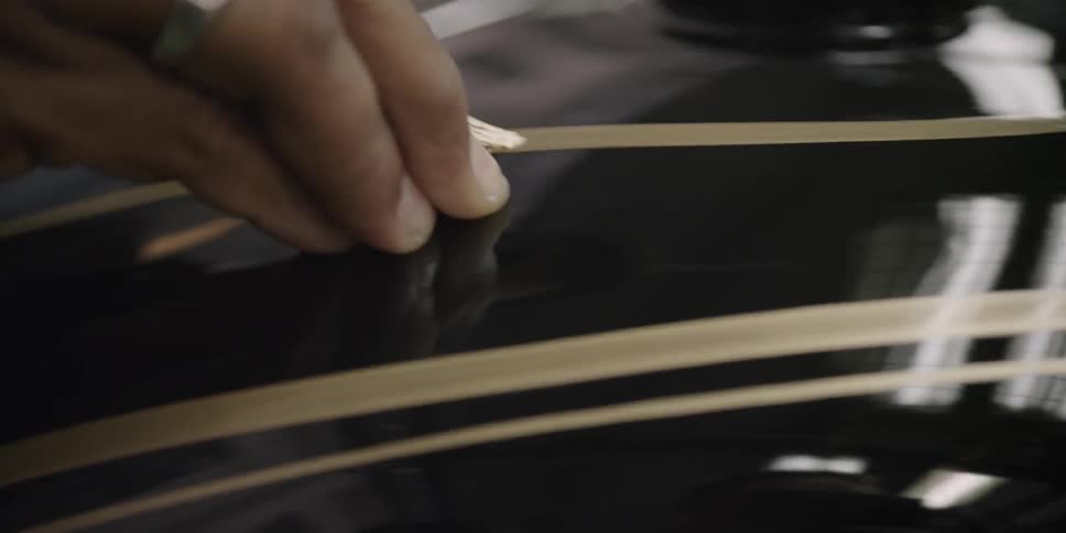 A painter applies a pinstripe to a tank