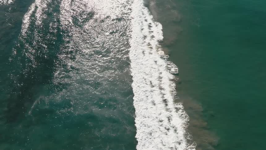 A wave breaking in the sea and making white foam on the surface of the water