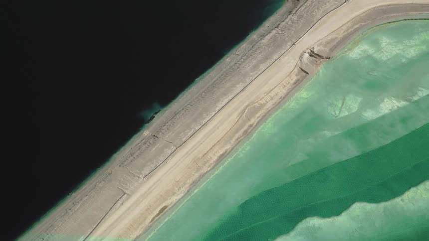 Aerial panorama of a road through industrial reservoirs in shades of blue and green