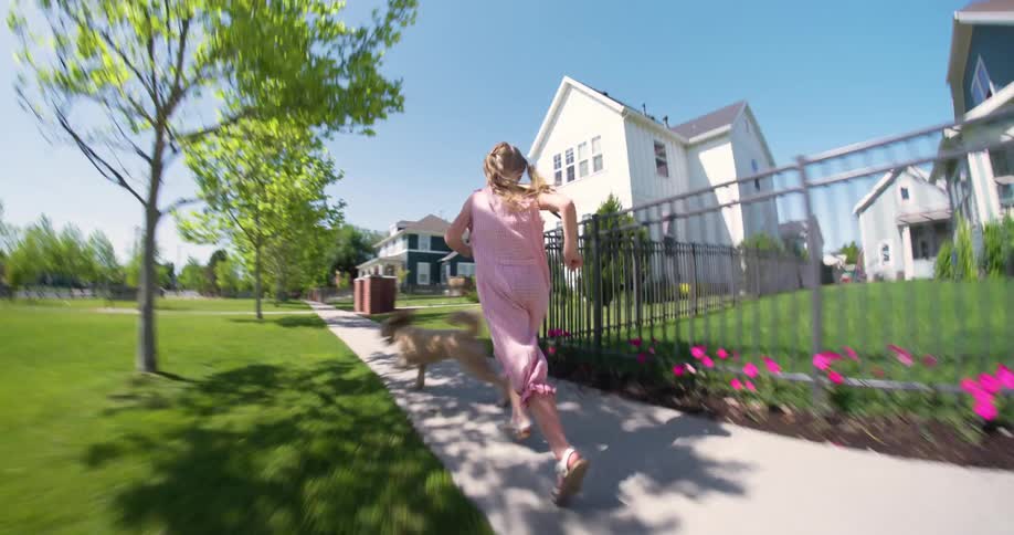 Young girl and her dog running on pathway through the community neighborhood