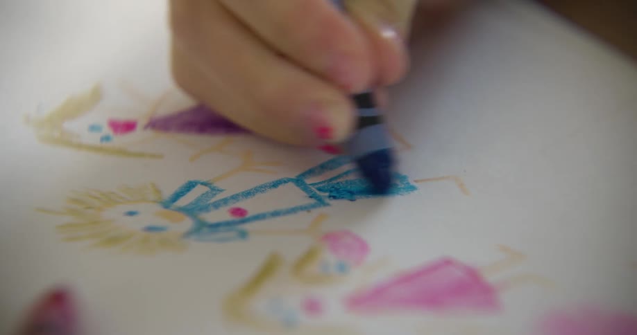 A child coloring a drawing with a blue crayon on white paper